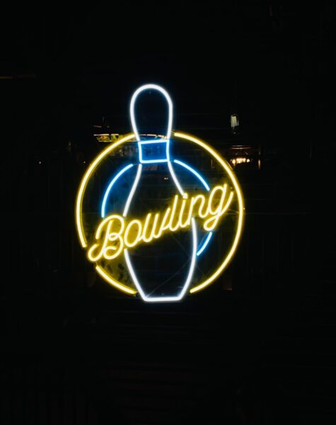 a neon bowling sign lit up in the dark